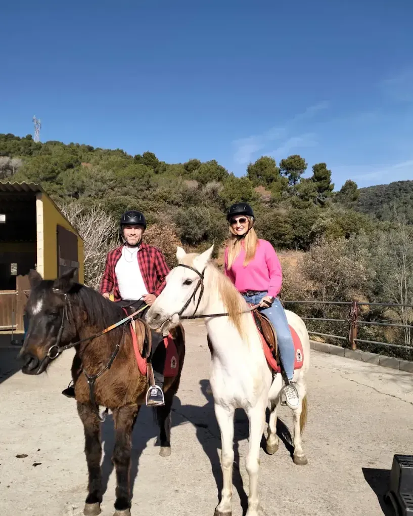 Un hombre y una mujer montan a caballo en un camino de tierra.