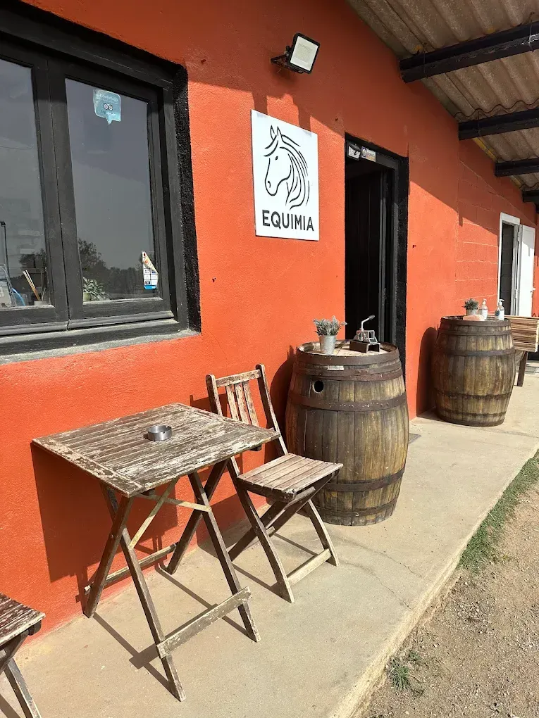 Una mesa y sillas de madera están ubicadas afuera de un edificio.