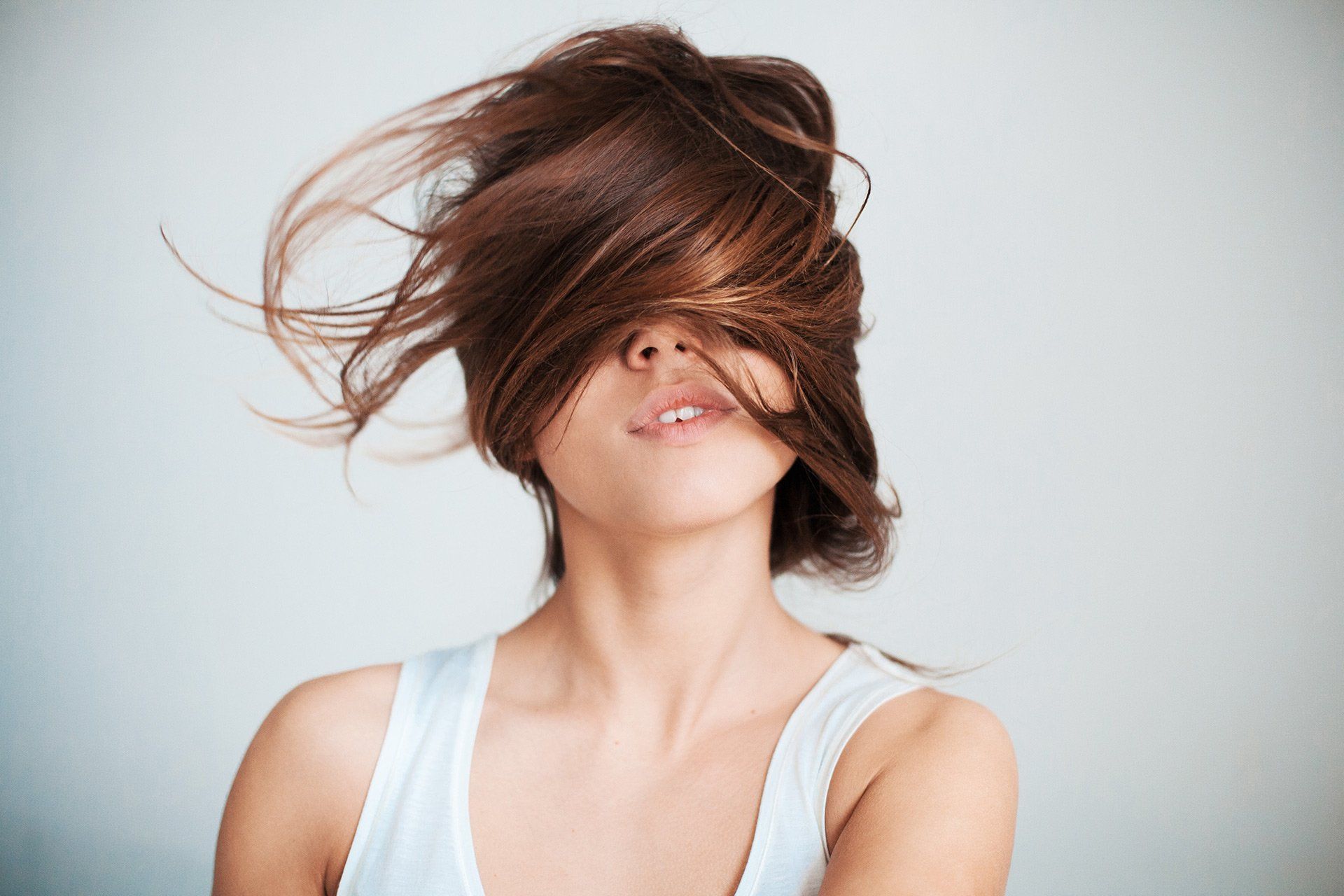 Una mujer con su cabello ondeando al viento cubriéndole la cara.