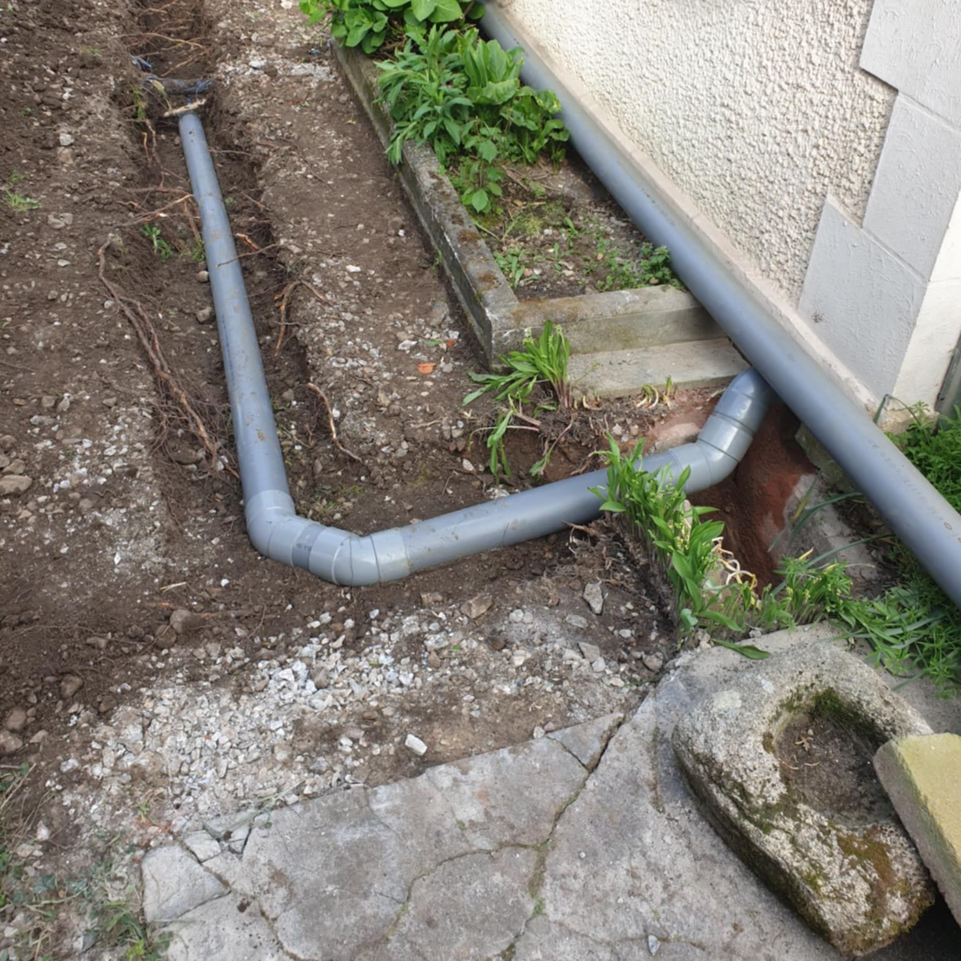 Tuyaux en PVC installés sous terre à côté d'une maison.
