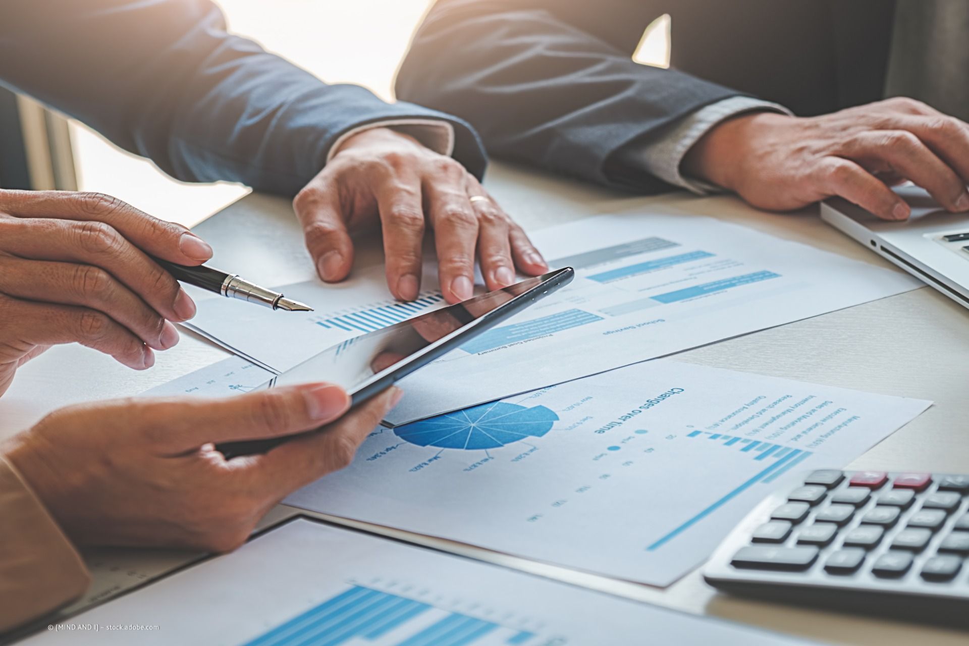 Peter Lennartz Steuerberater – drei Personen in einem Meeting am Schreibtisch voller Flowcharts und Finanzdaten