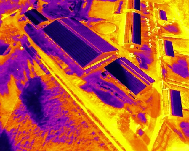 Wärmebildansicht eines Bauernhofs mit Gebäuden: violette Dächer, gelber Boden.