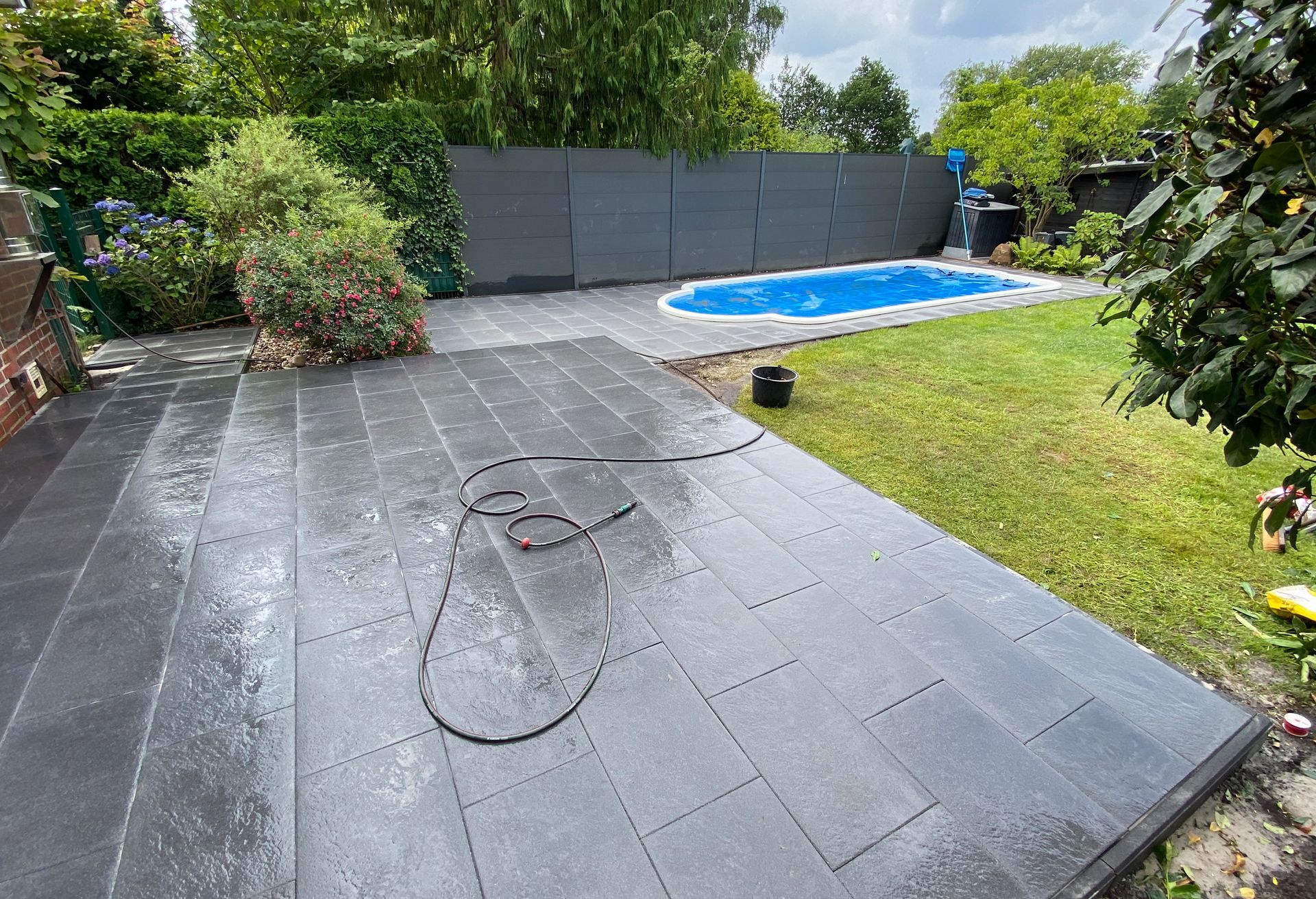 Ein Schlauch liegt auf einer Terrasse neben einem Pool.