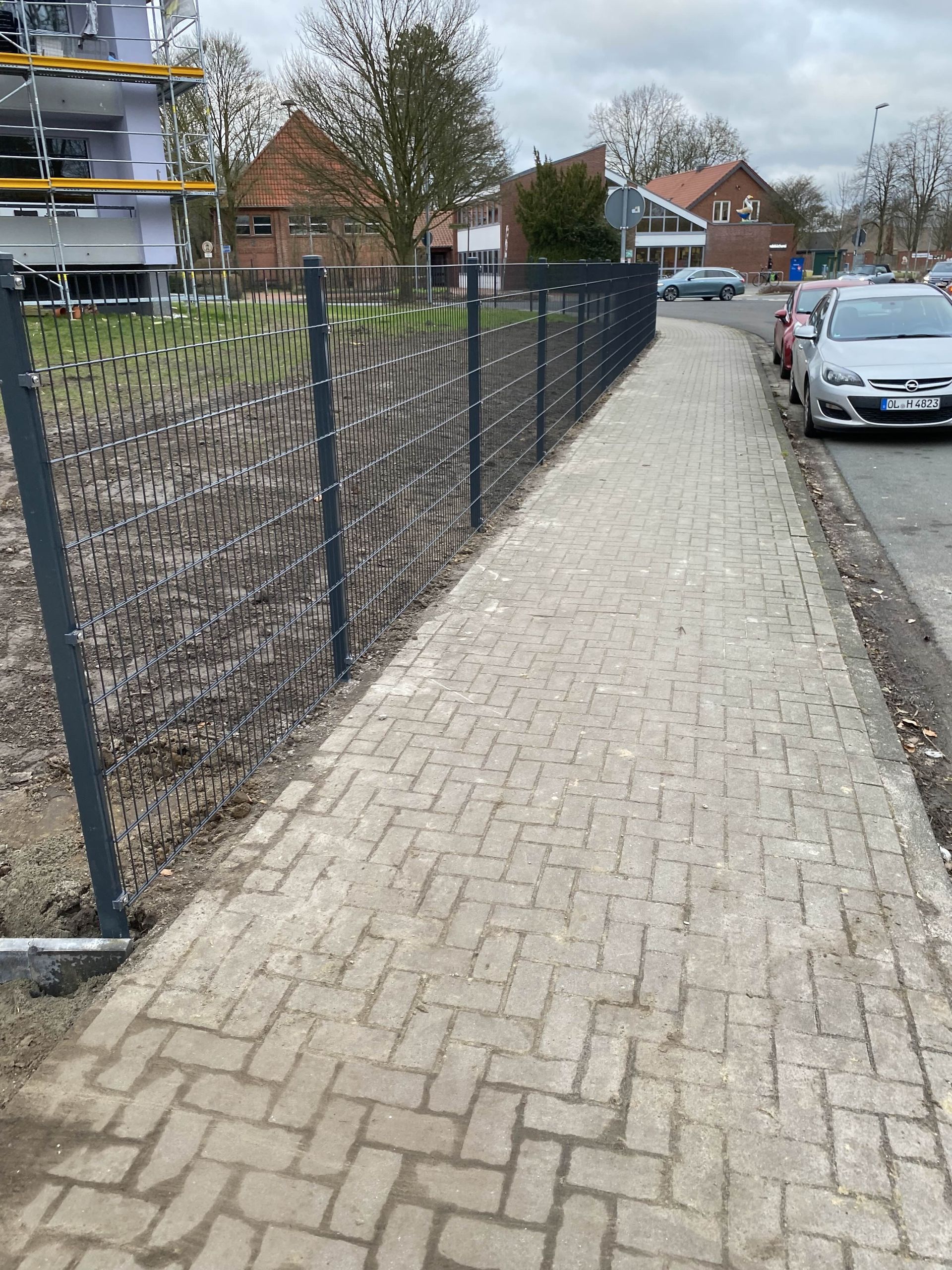 Eine Reihe Holzbänke steht auf einem gepflasterten Gehweg in einem Park.