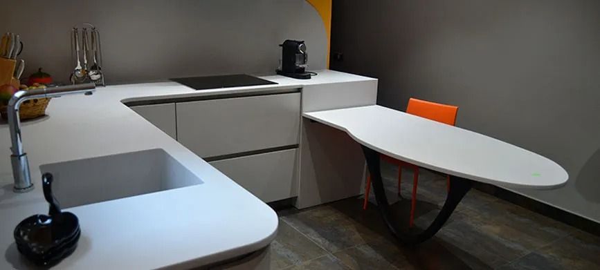 Oficina moderna con escritorios blancos, sillas naranjas y una silla giratoria oscura sobre suelo de madera.