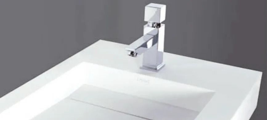 Lavabo de baño moderno blanco con grifo cromado sobre una pared gris.
