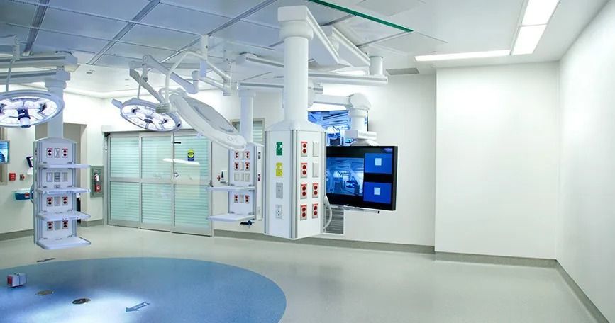 Sala de tratamiento hospitalario moderna con equipamiento médico, paredes blancas y suelo azul.