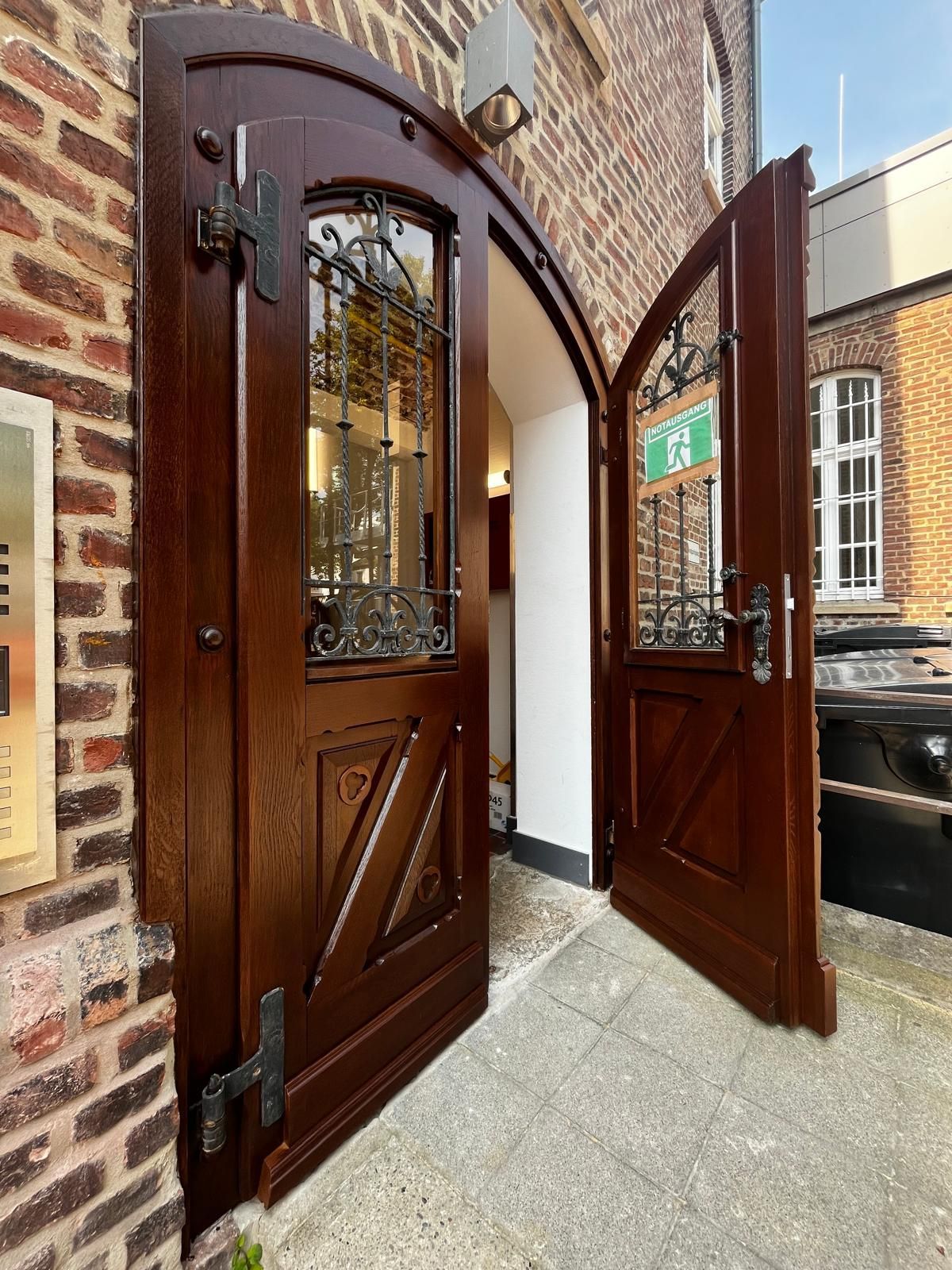 Runde Holztür mit geschwungenen Fenstergittern