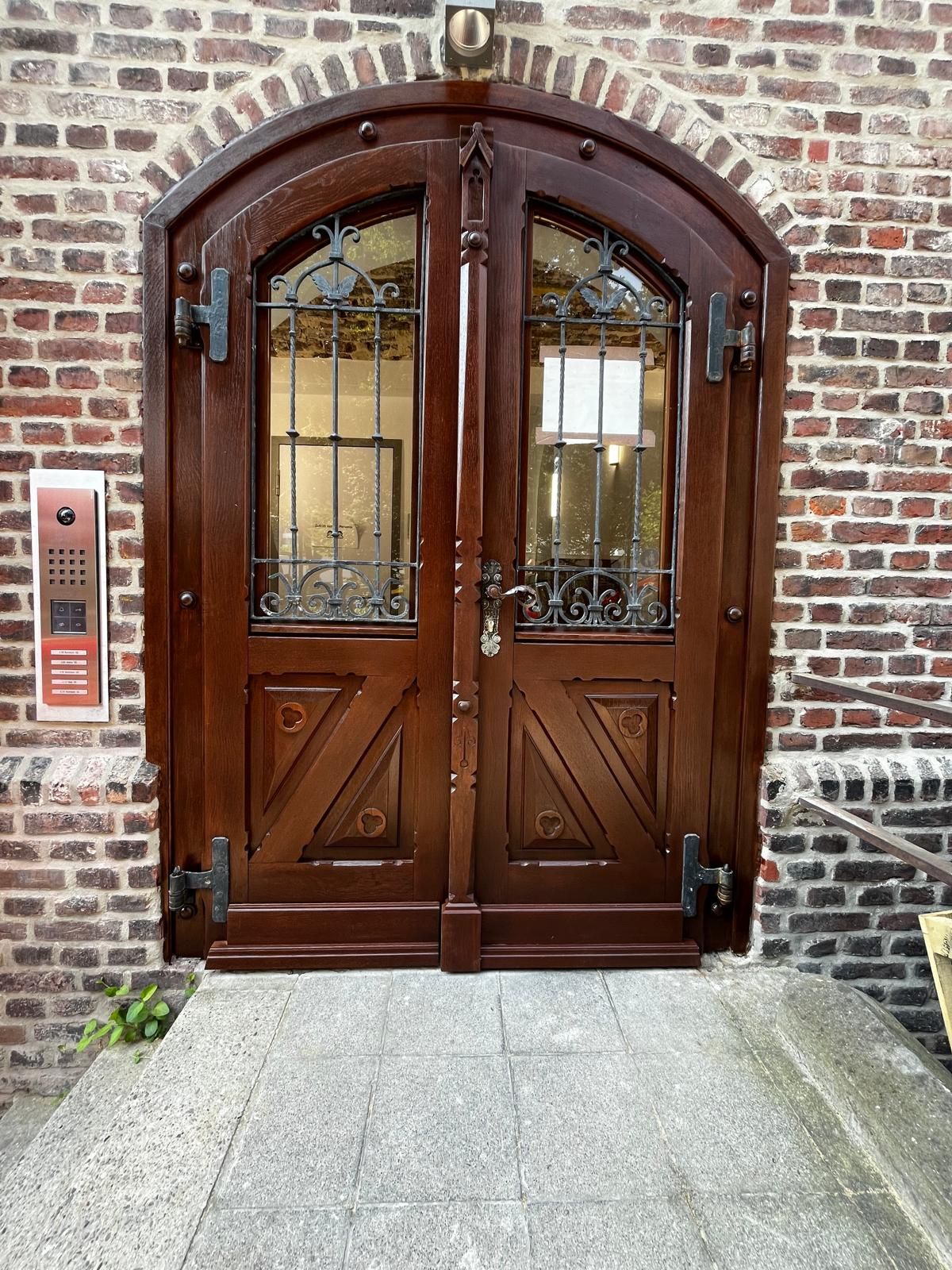 Eingangstür mit Rundung im Vintagestil mit verschnörkelten Eisenbeschlägen und -gittern vor den Fenstern