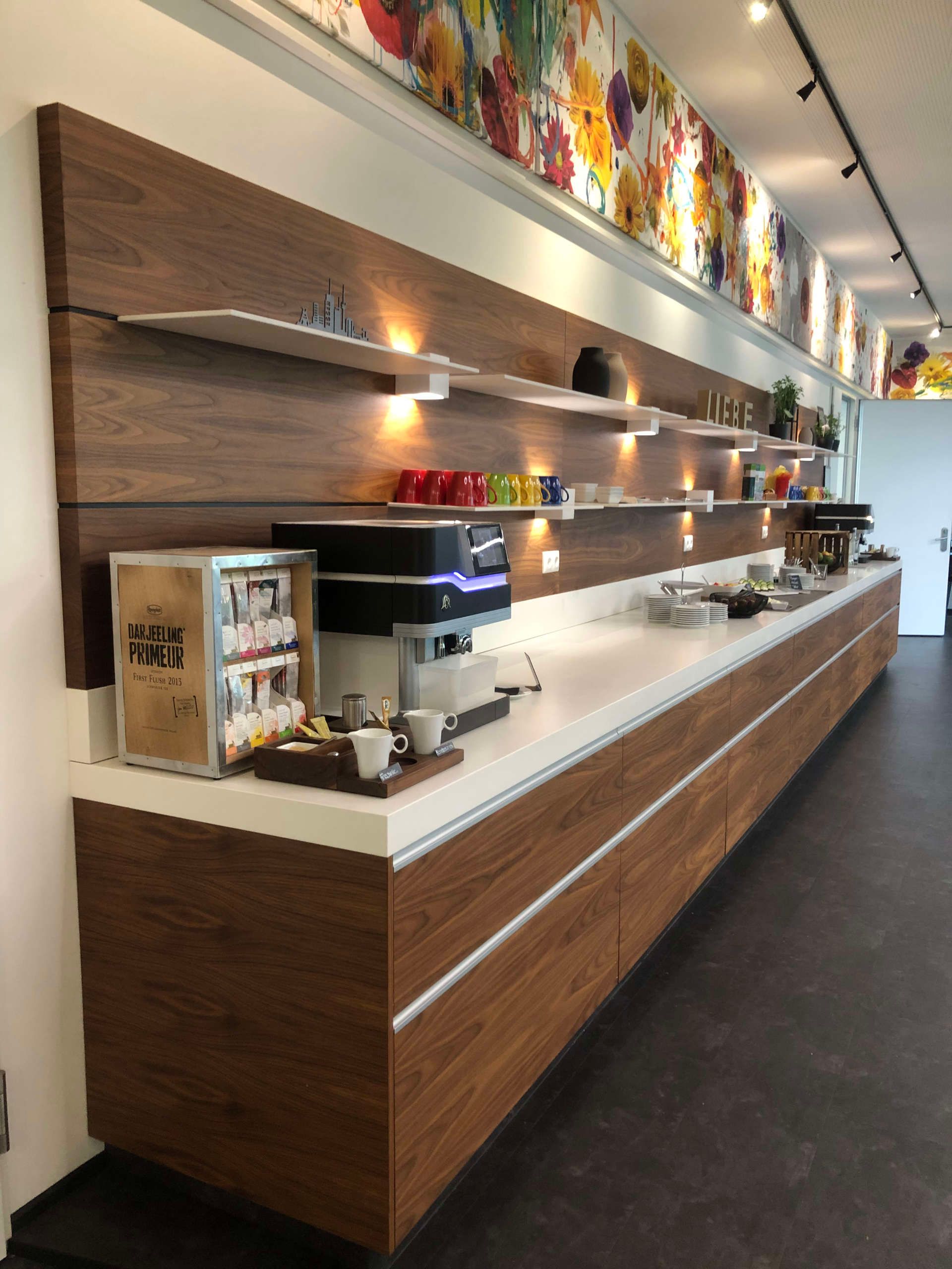 Lange Küchenzeile mit integrierter Beleuchtung in dunklem Holz und weißer Arbeitsfläche