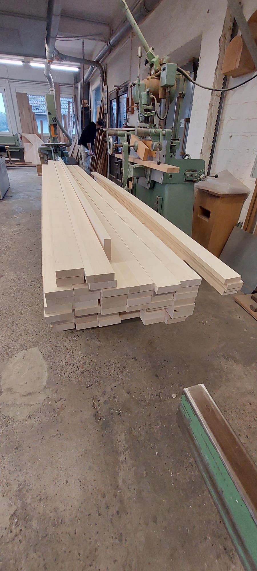 In einer Werkstatt liegt ein Stapel Holz auf dem Boden.