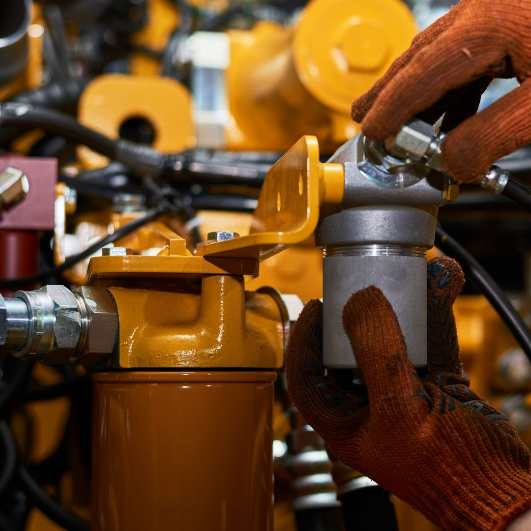 Des mains gantées d'orange réparent des machines.