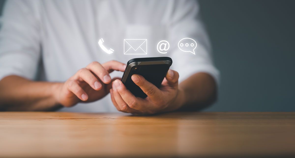 Une personne utilisant un smartphone avec des icônes de contact (téléphone, e-mail, chat) superposées.