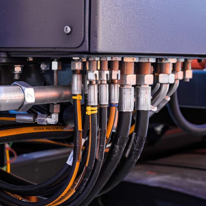 Gros plan sur une machine industrielle avec de multiples tuyaux et raccords hydrauliques connectés.