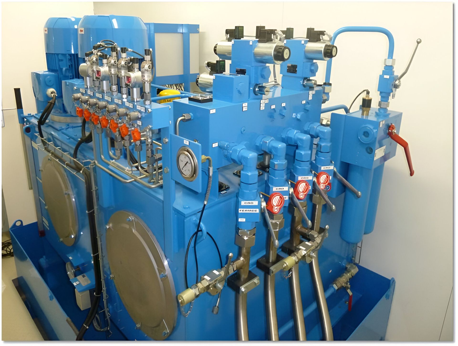 Groupe hydraulique industriel bleu avec diverses vannes, tuyaux et manomètres.