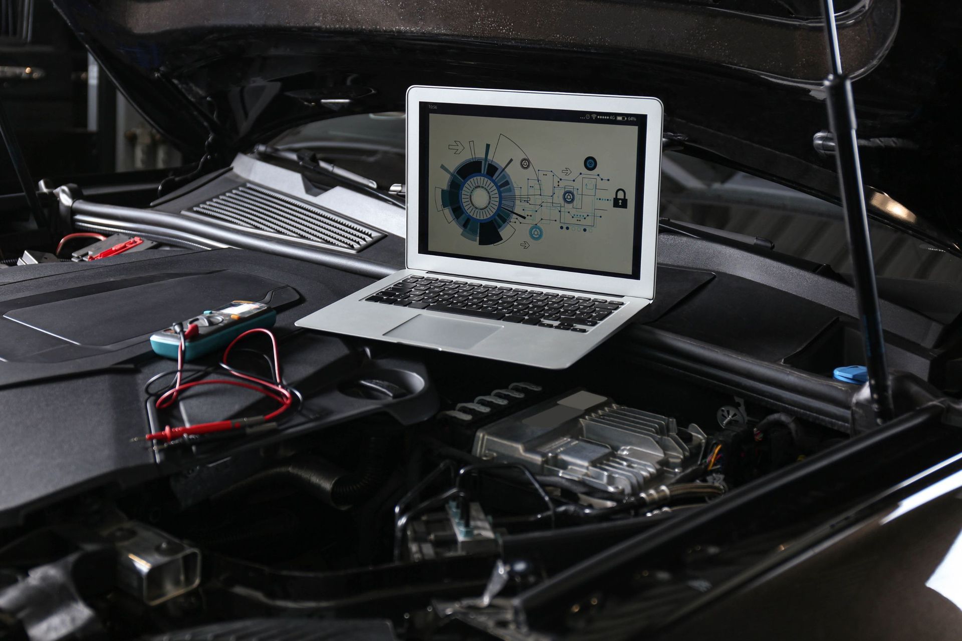 Una computadora portátil está debajo del capó de un automóvil.