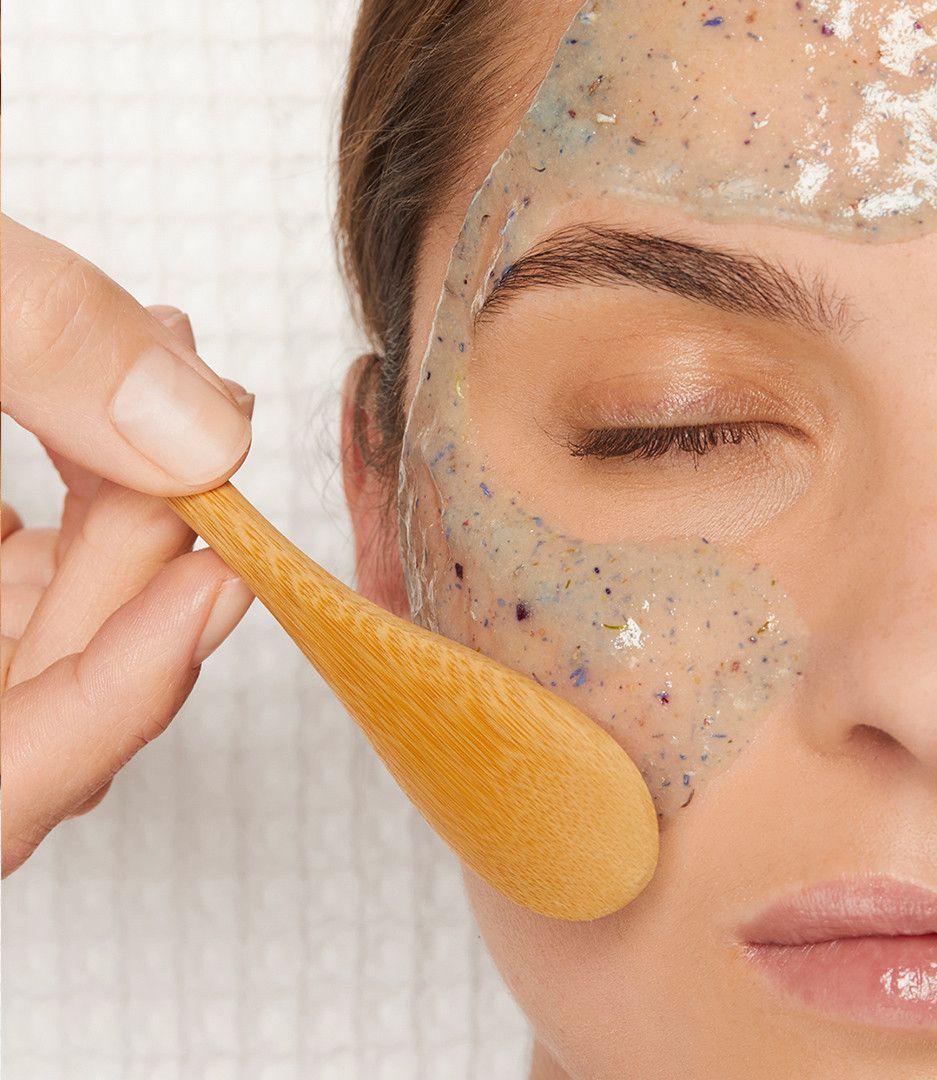Application d’un masque facial au pinceau sur la joue d’une personne, en gros plan, les yeux fermés
