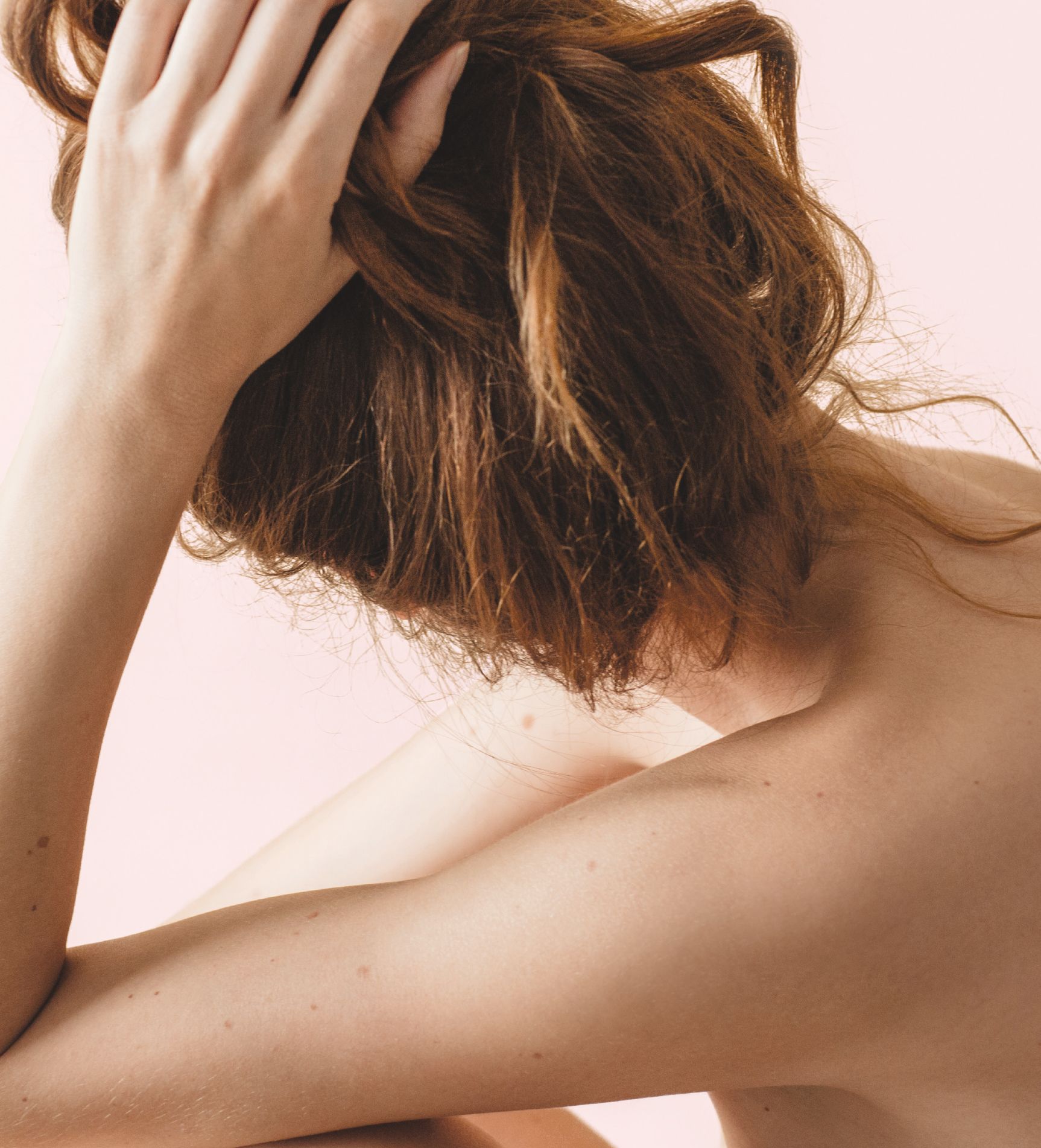 Personne aux cheveux bruns qui les attache sur fond rose pâle