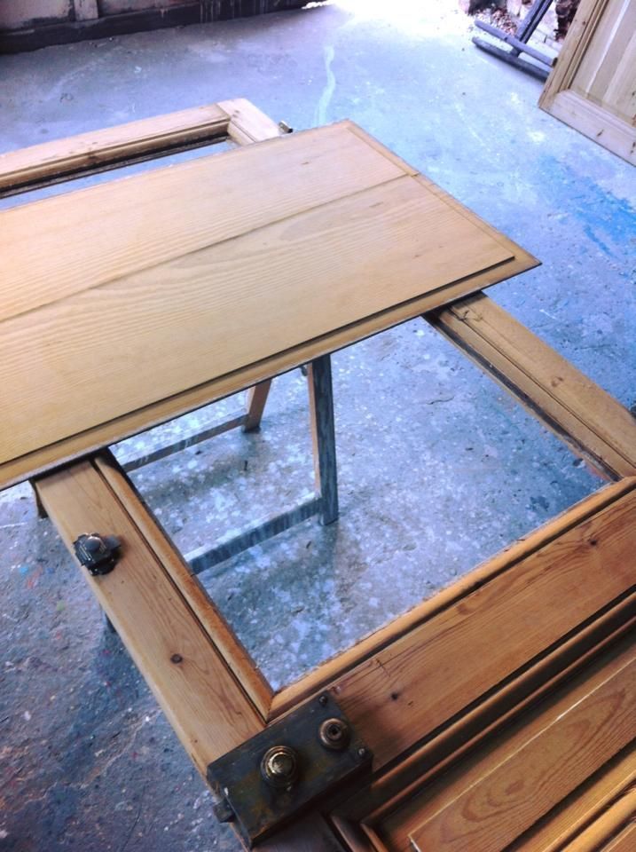 Cadre et panneau de porte en bois reposant sur un tréteau, en cours de restauration.