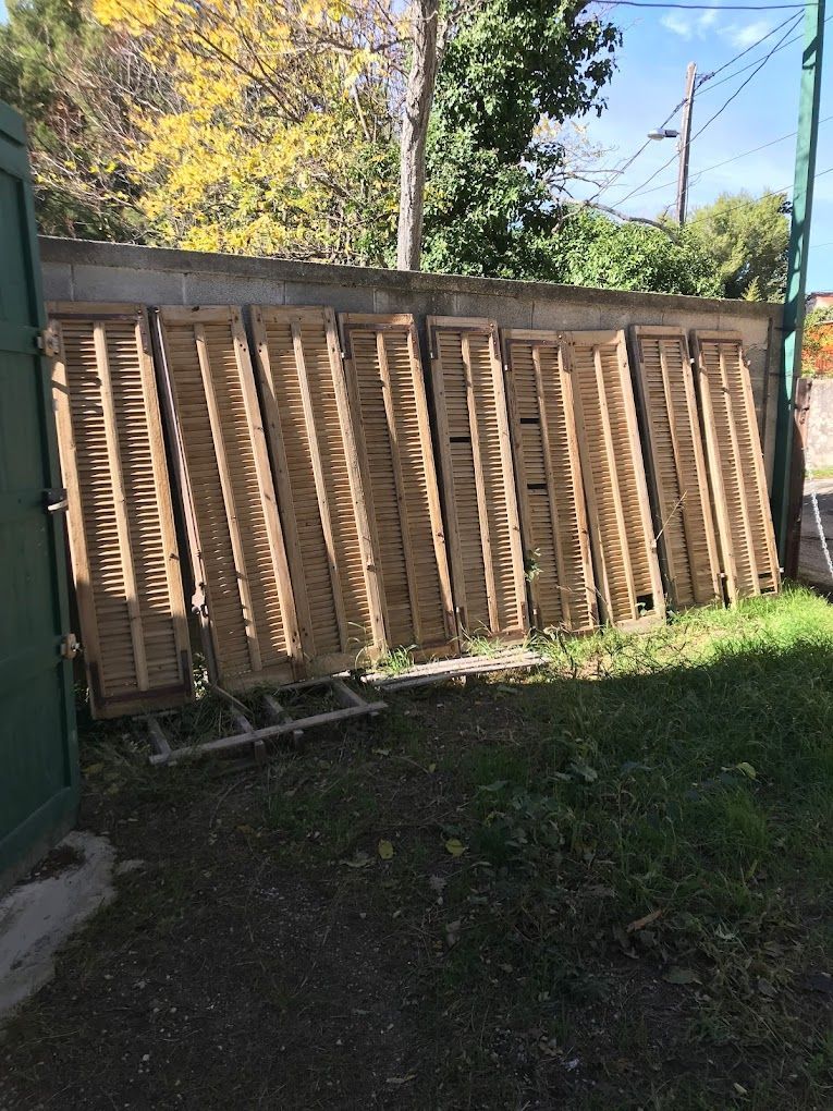 Volets en bois appuyés contre un mur, à l'extérieur.
