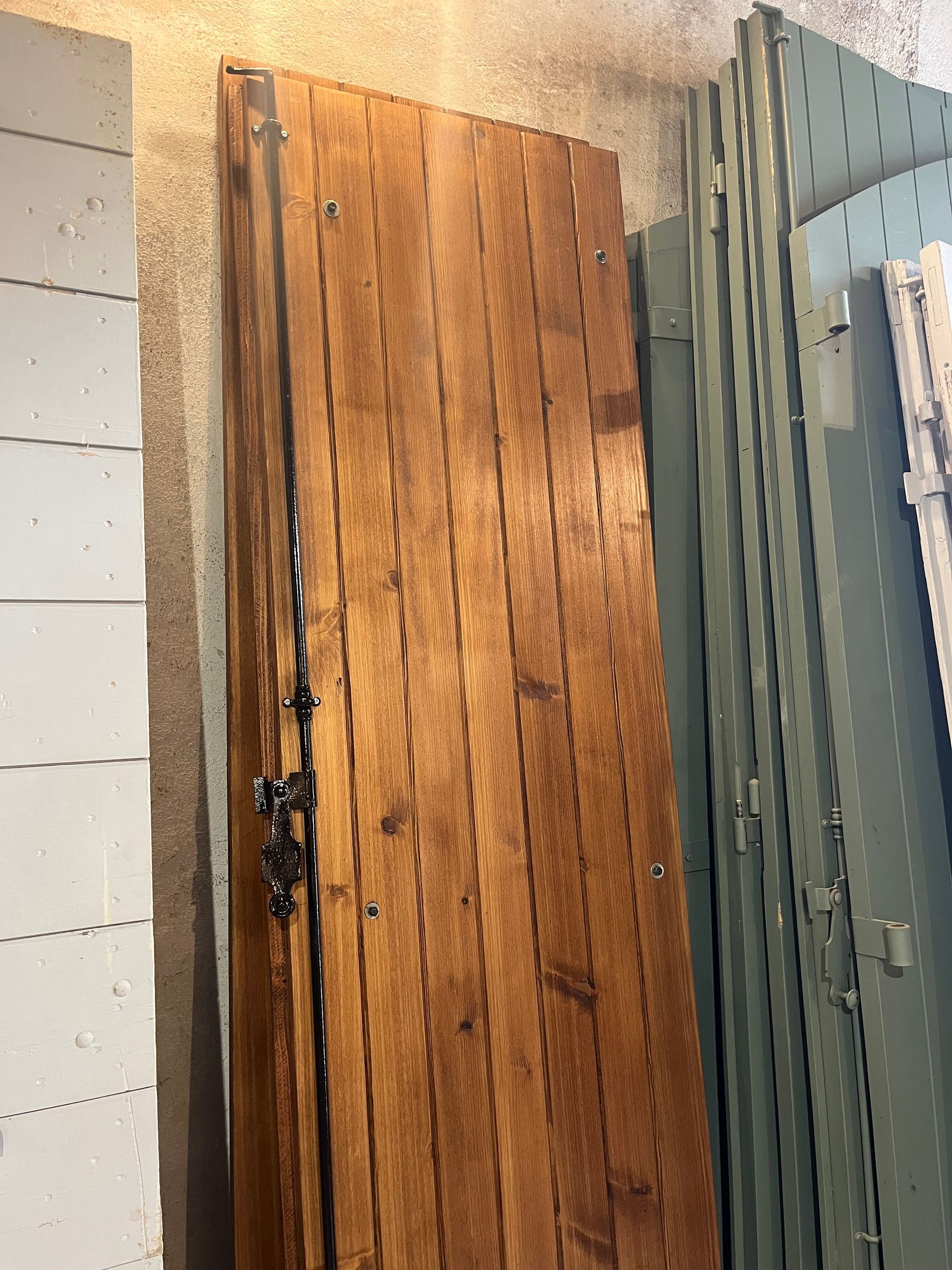 Volet en bois avec quincaillerie foncée, appuyé contre des étagères.