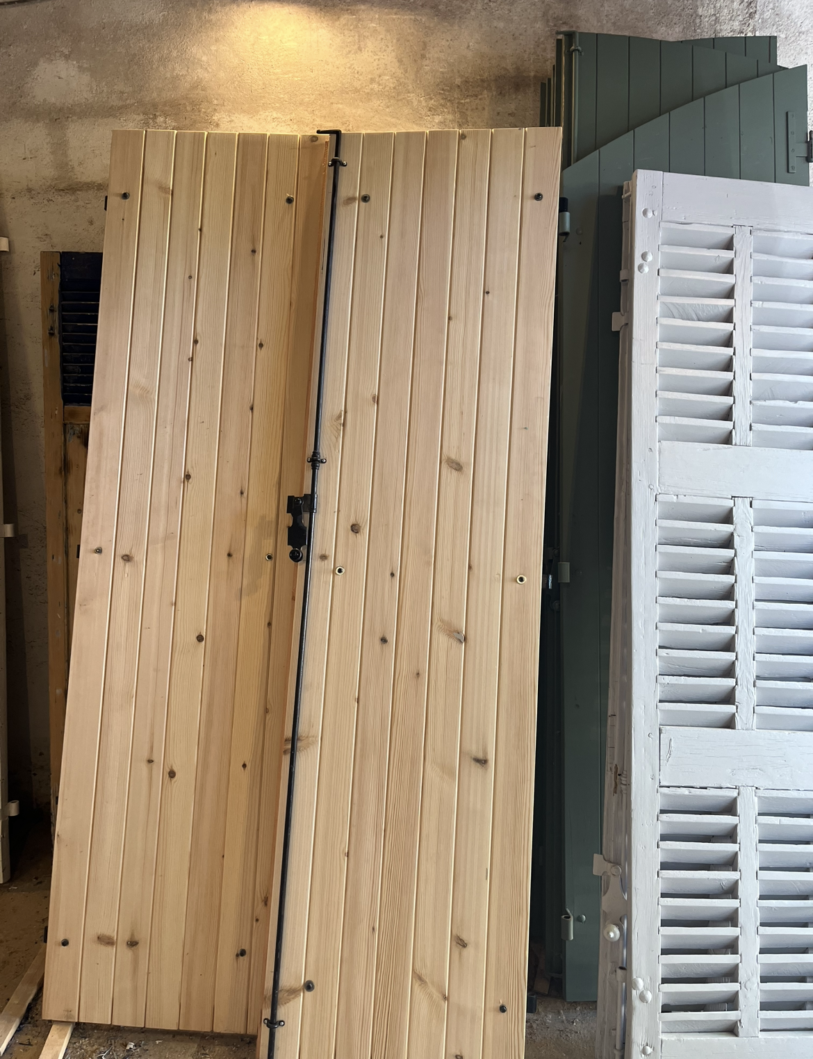 Volet en bois appuyé contre d'autres volets, y compris des portes à persiennes.