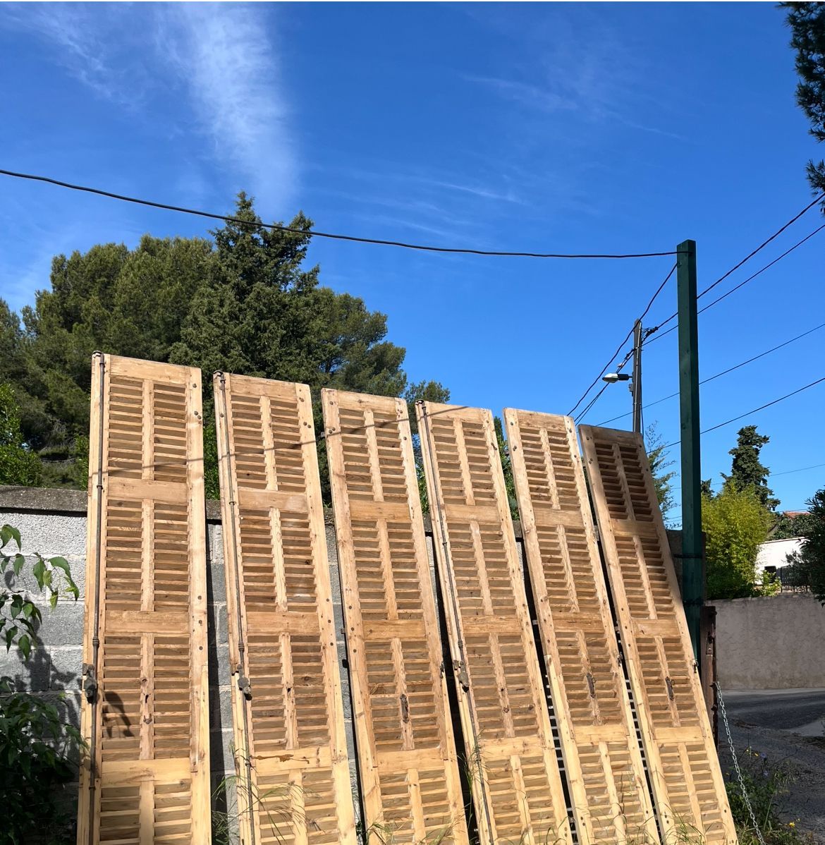 Volets en bois appuyés contre un mur extérieur par une journée ensoleillée.