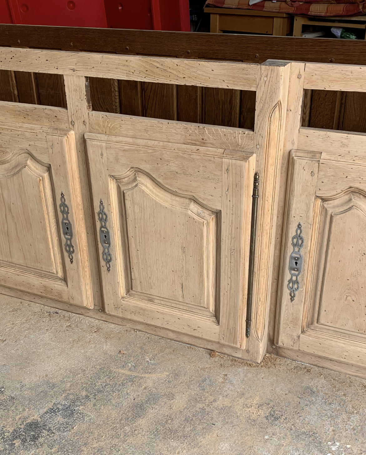 Trois portes d'armoire en bois clair teinté, ornées de poignées travaillées. Le dessus et le fond en bois foncé sont visibles.