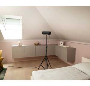 Ein Schlafzimmer mit einem Bett und einem Projektor auf einem Stativ.