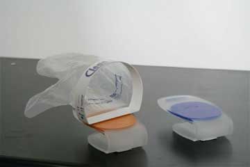 Auf einem Tisch liegt eine Plastiktüte neben einem Paar Fersenkappen.