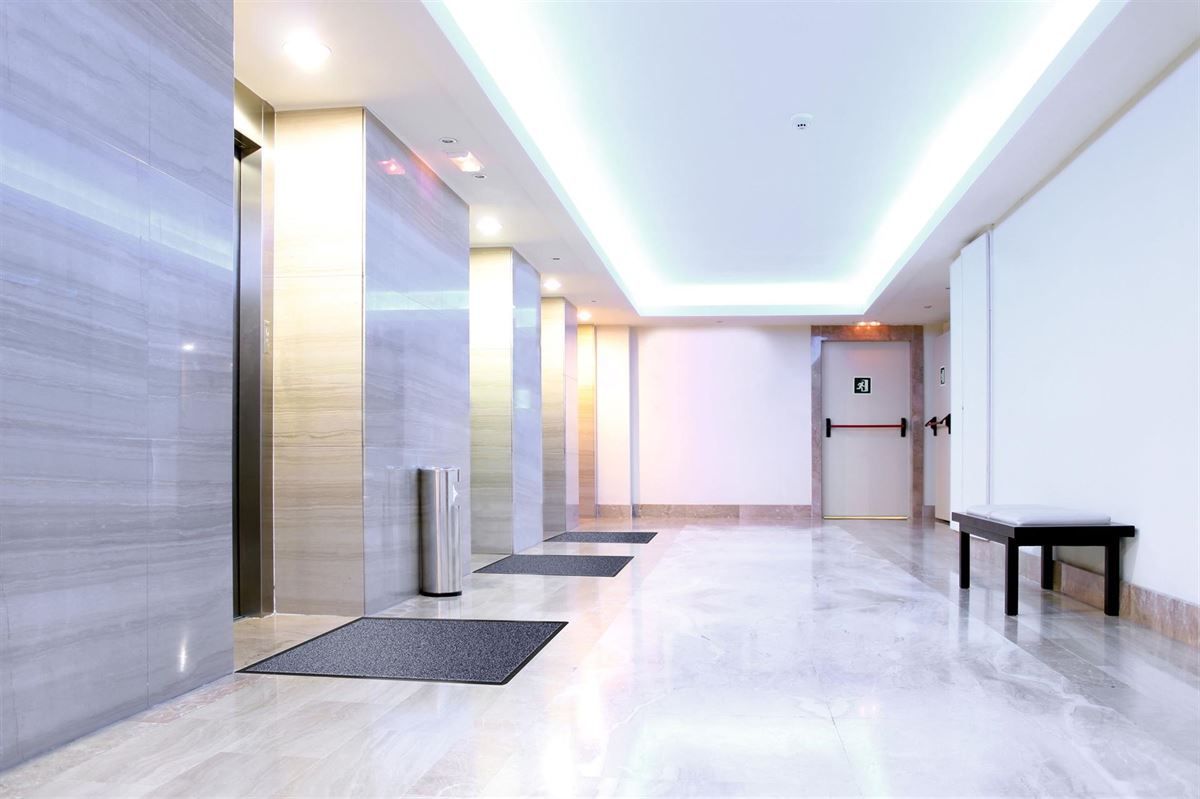 Ein Flur in einem Gebäude mit Aufzügen und einer Bank