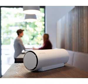 Ein weißer Lautsprecher steht auf einem Holztisch.