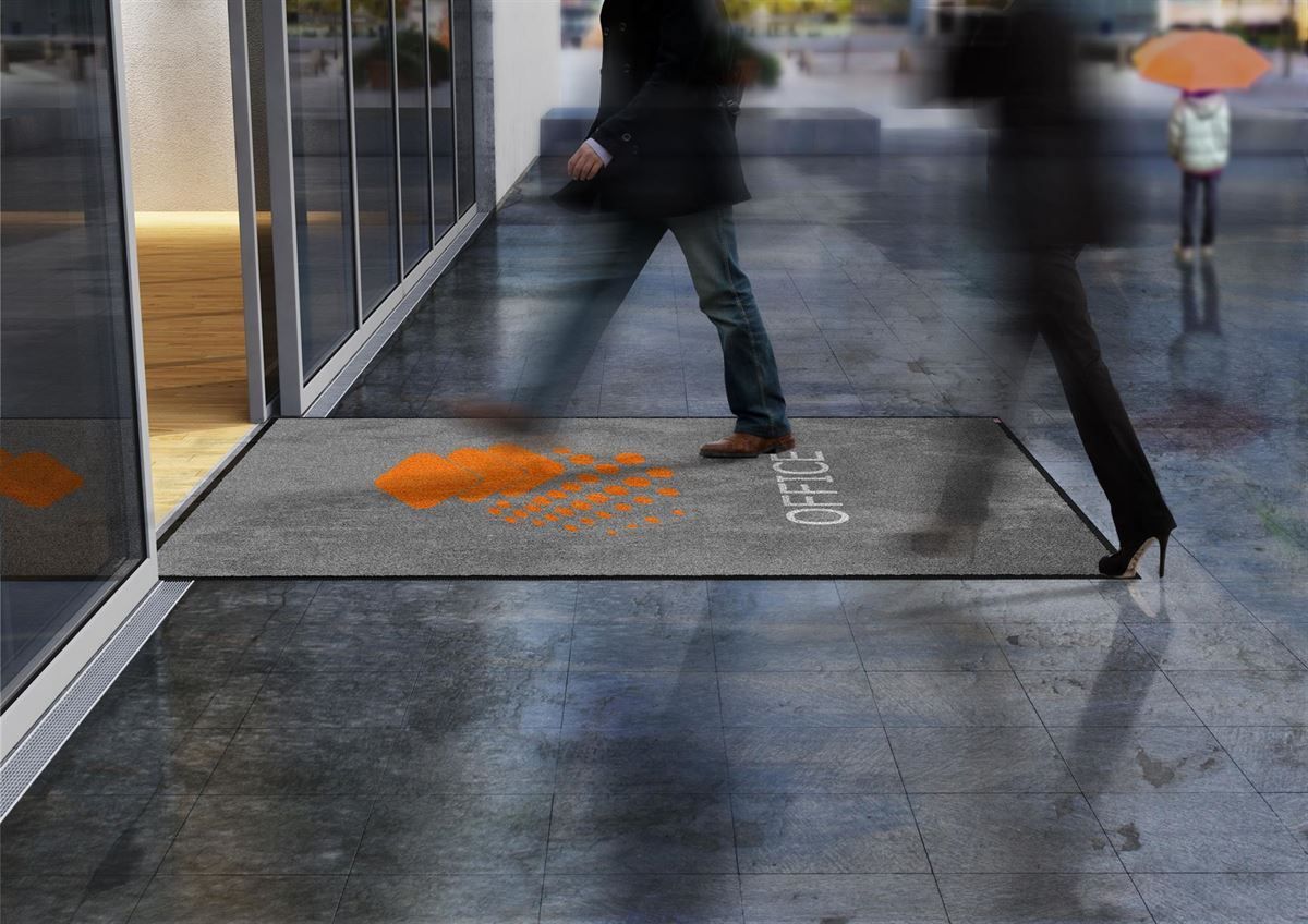 Ein verschwommenes Bild von Menschen, die auf einem Bürgersteig mit einer Matte laufen, auf der „tlp“ steht