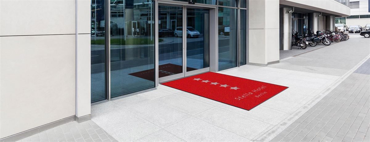 Eine rote Matte liegt auf dem Bürgersteig vor einem Gebäude