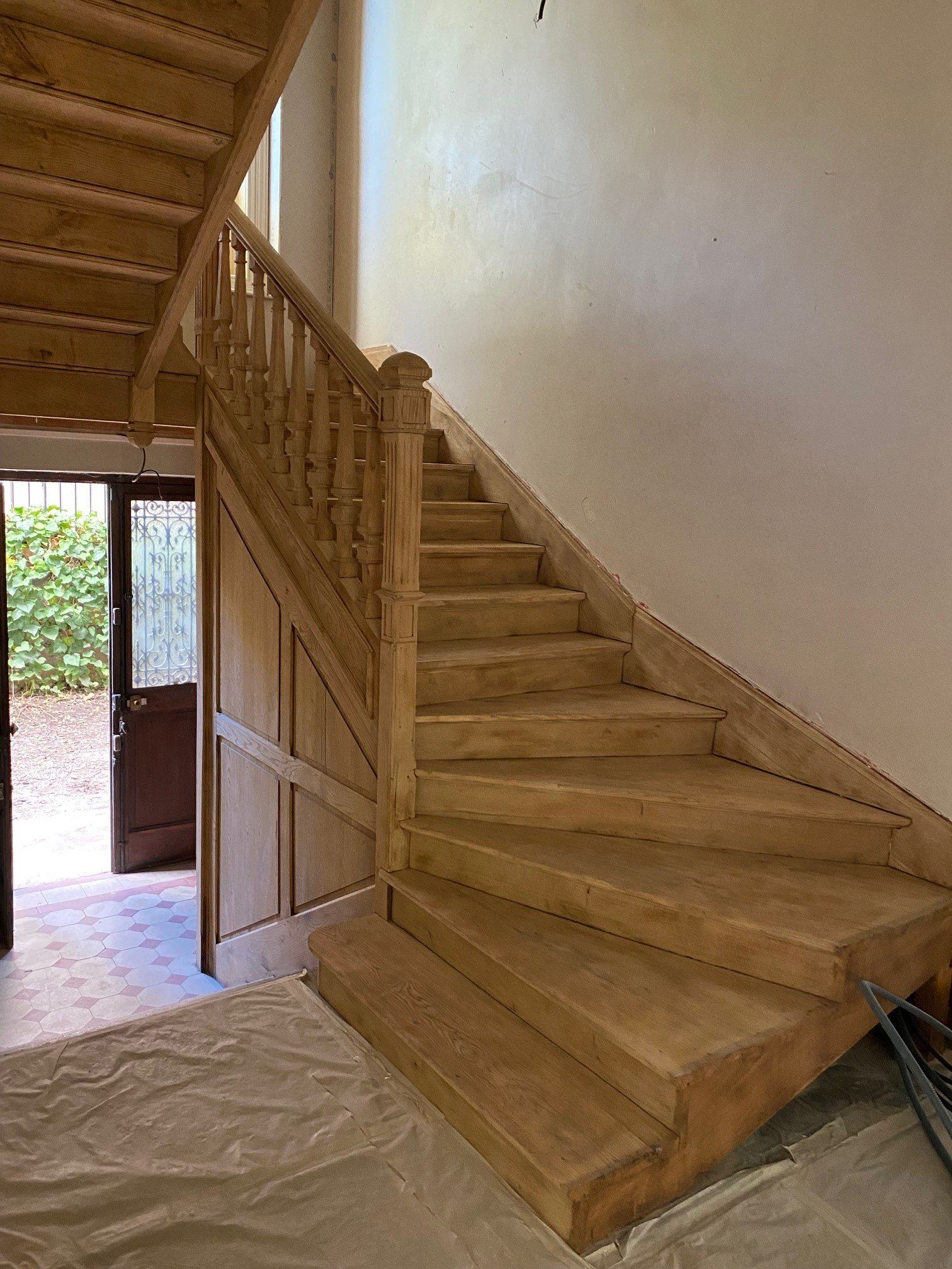 Cage d'escalier en bois clair avec une porte ouverte