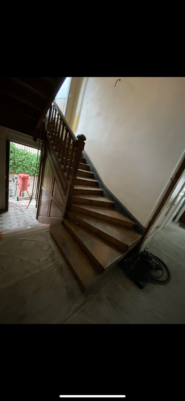 Cage d'escalier en bois foncé avec une porte ouverte