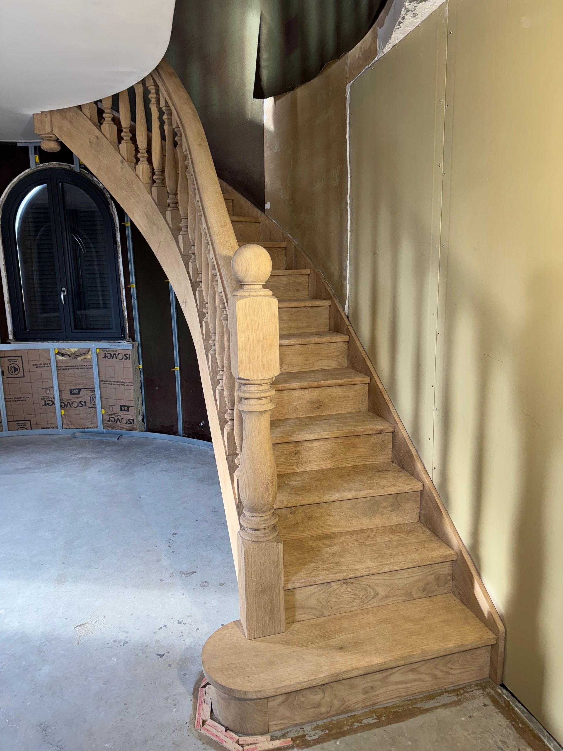 Mur en train d'être isolé à côté d'une cage d'escalier en bois clair