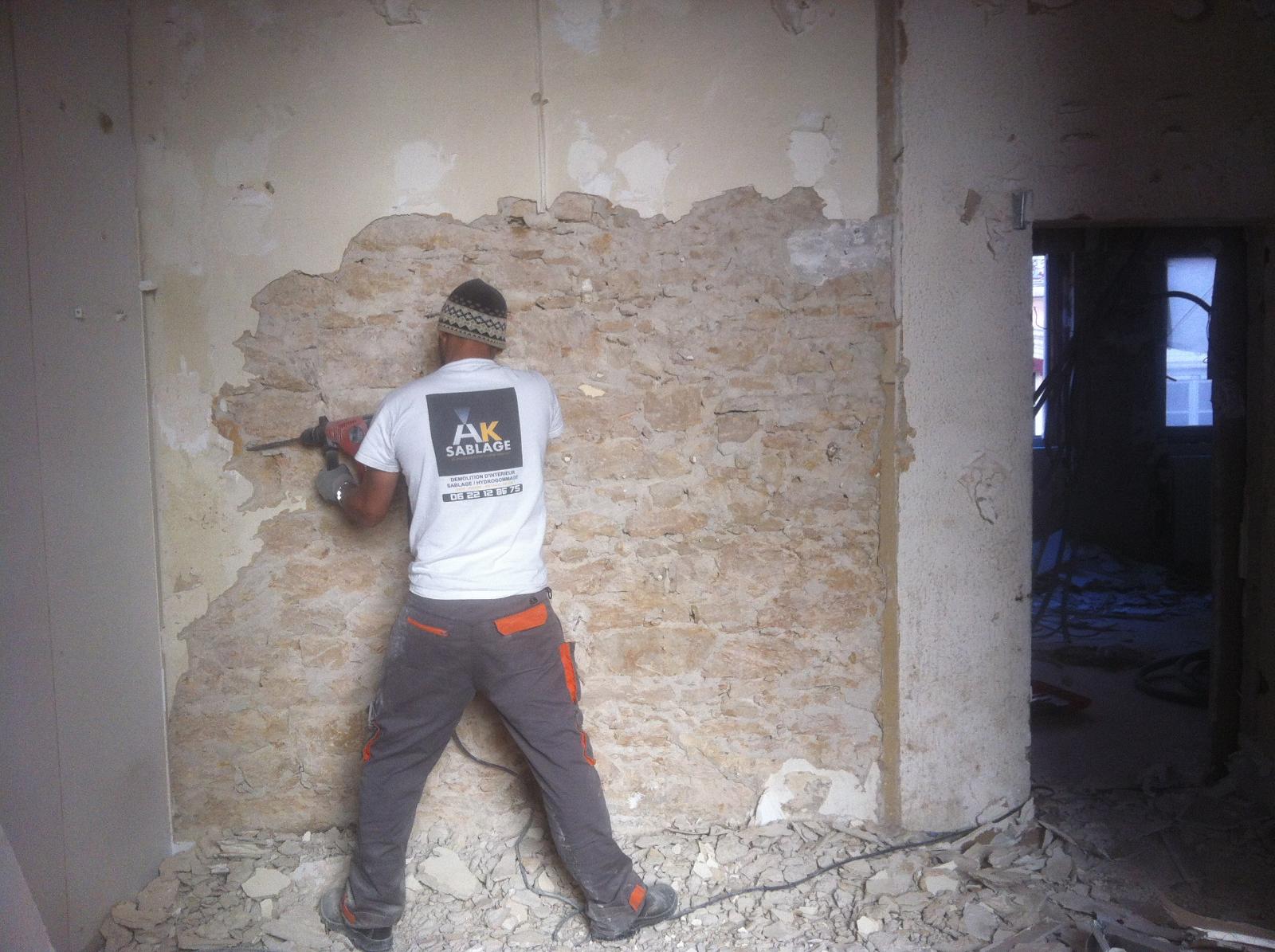 Artisan d'AK Sablage en train d'enlever le revêtement sur un mur