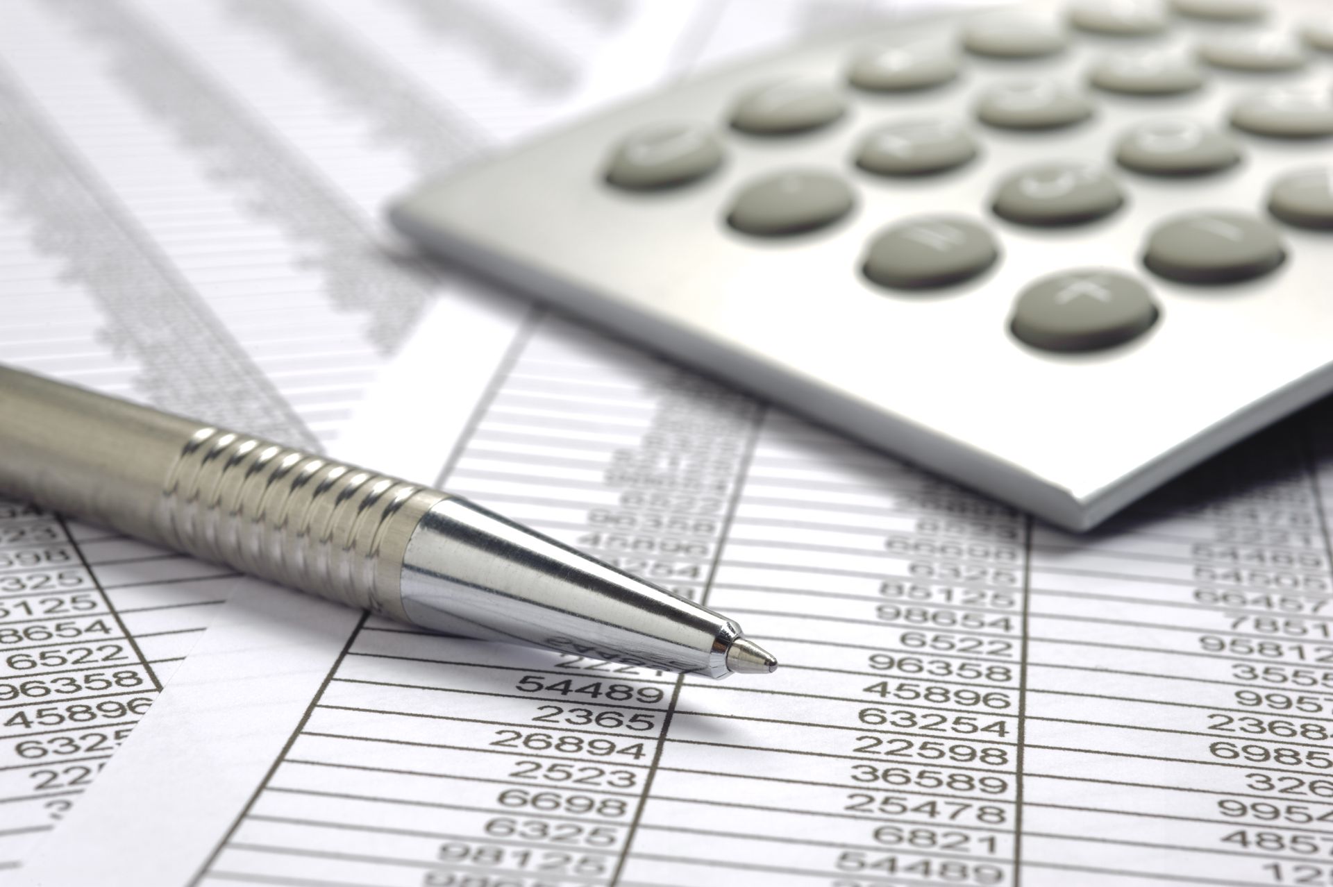 Lápiz y calculadora sobre una hoja de cálculo, sugiriendo análisis financiero o contabilidad.