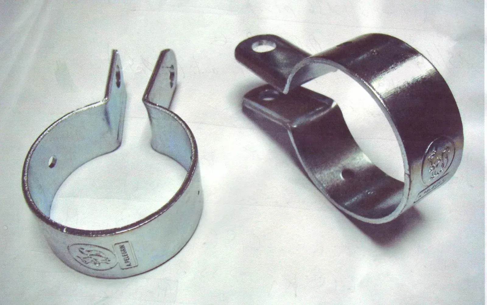 Dos soportes de metal doblados; uno de oro amarillo, otro de plata; ambos con orificios para montaje.