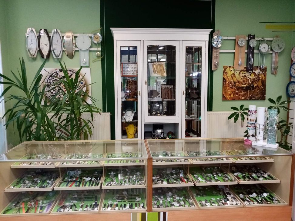 Eine Vitrine voller verschiedener Uhren umgeben von Wanduhren und Schmuck.