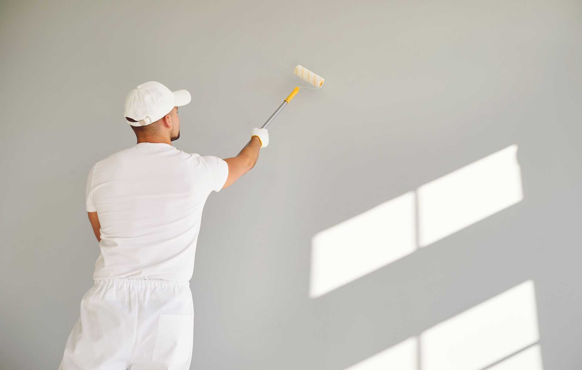 Un homme peint un mur avec un rouleau à peinture.