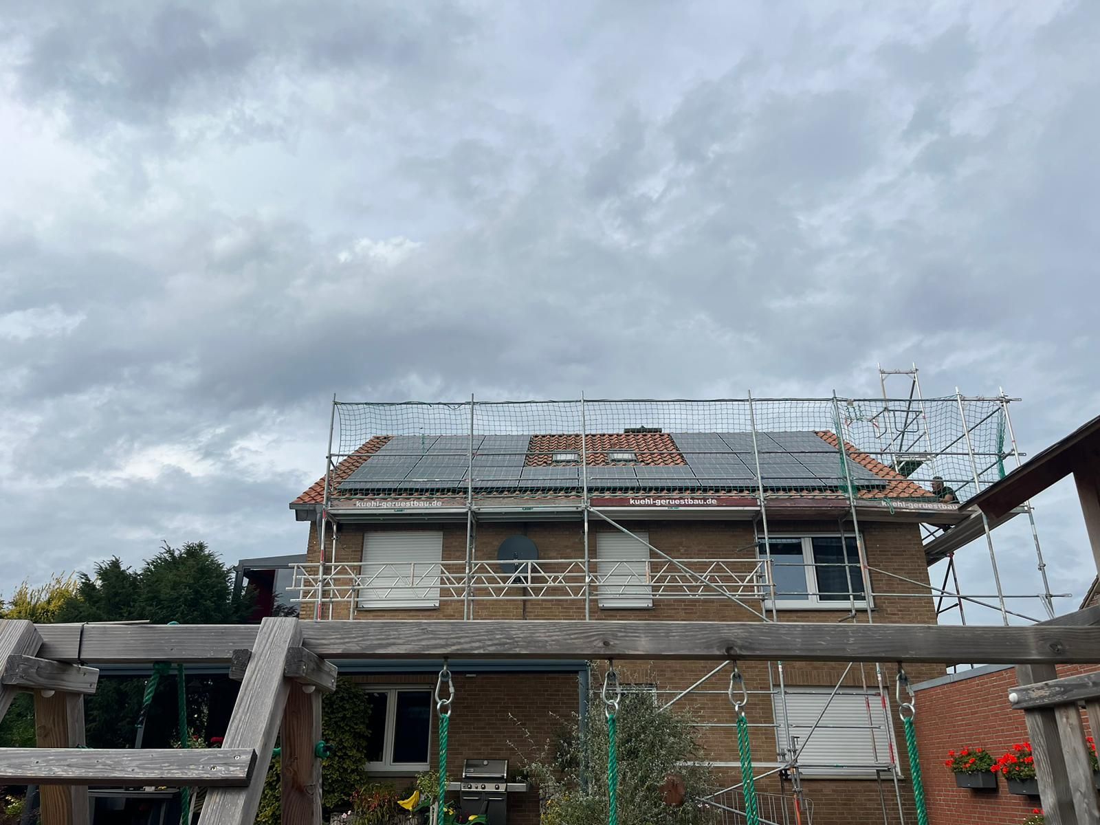 Haus im Bau mit Gerüsten und bewölktem Himmel.