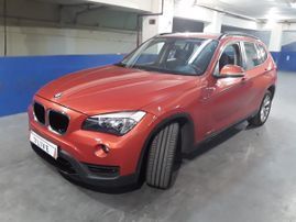 Un BMW X1 rojo está aparcado en un garaje.