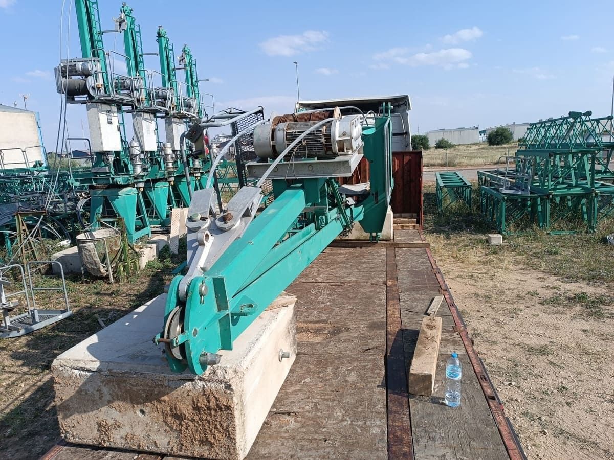 Una gran máquina agrícola verde estacionada en una plataforma de concreto al aire libre, en un día soleado.