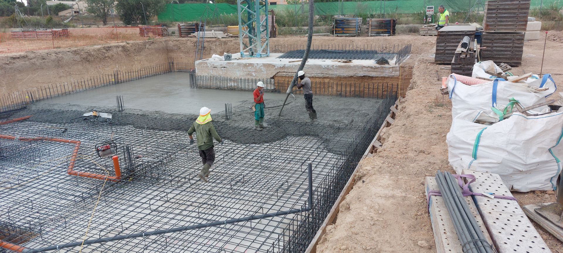 Obreros de la construcción vierten hormigón en los cimientos de una obra en construcción.