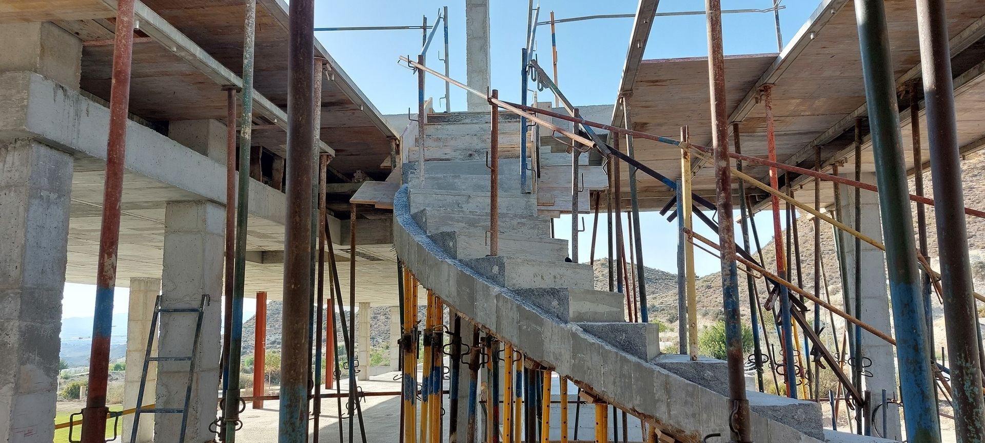 Escalera de hormigón en construcción, sostenida por andamio.