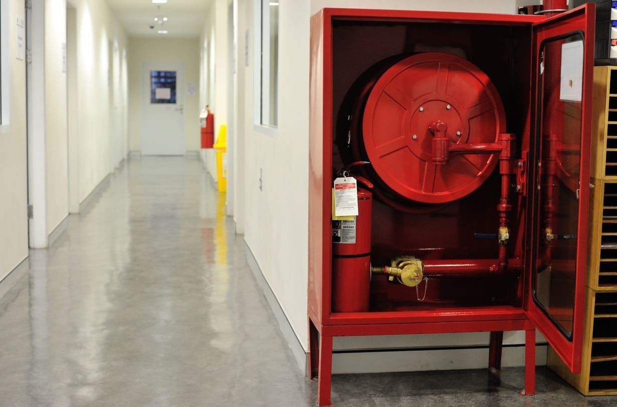 Una boca de incendios roja en un pasillo con la puerta abierta