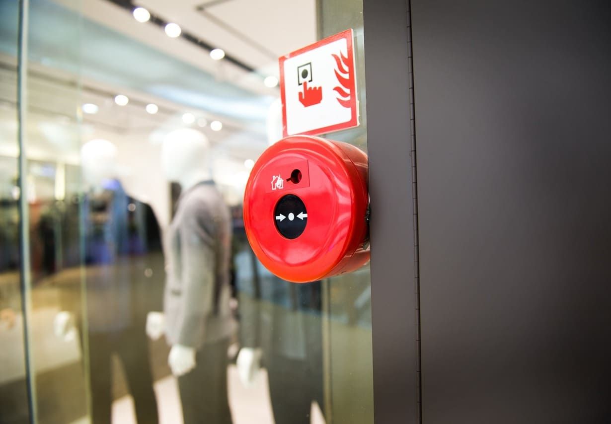 Una alarma de incendios roja está colgada en una puerta de vidrio en una tienda.