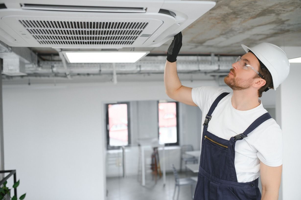 Un hombre está trabajando en un ventilador de techo en una oficina.